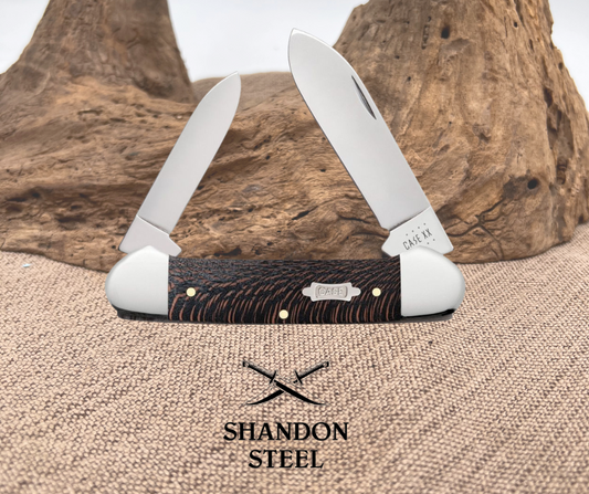 A folded Case Canoe pocket knife with a black sycamore handle and nickel silver bolsters and inlay, displayed against a natural background.