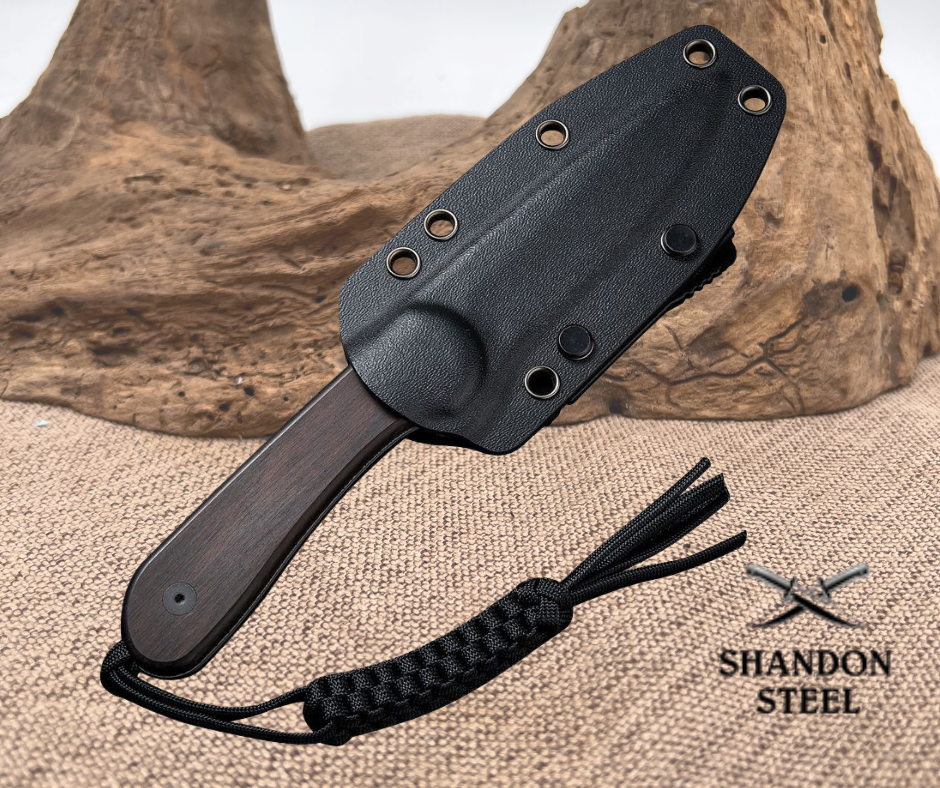 Black knife with sheath on a textured surface, Shandon Steel branding visible