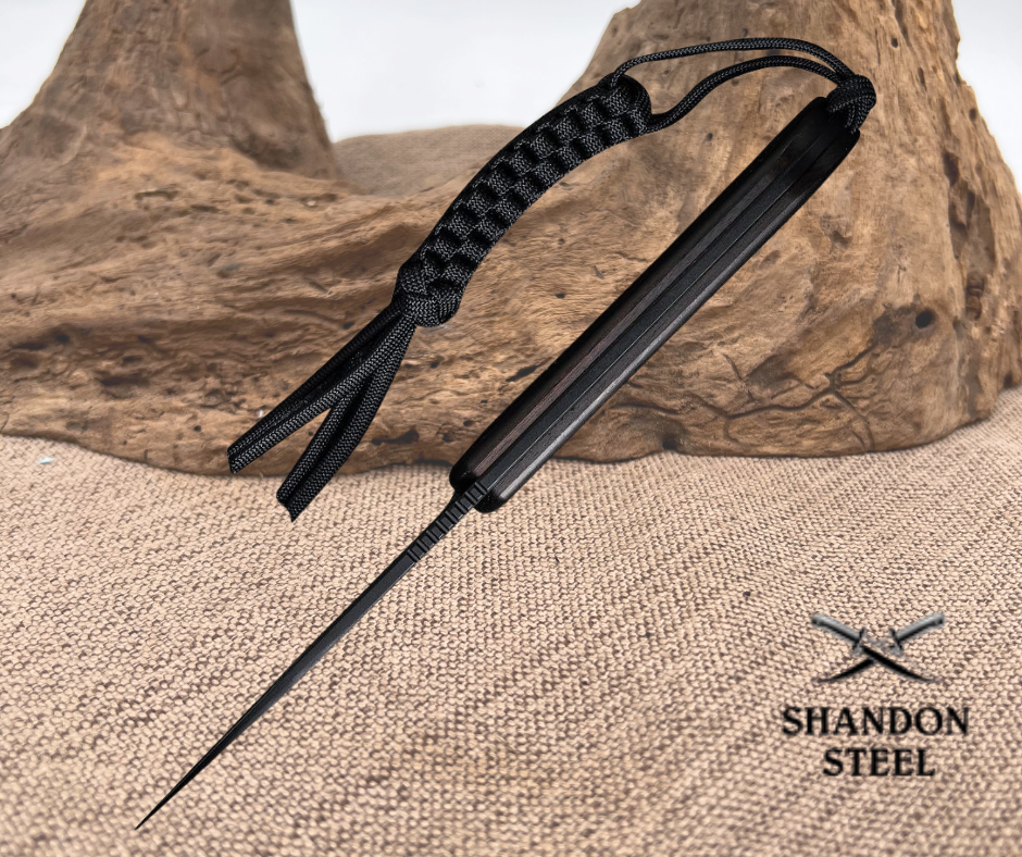 Black knife with a textured handle on a stone surface, Shandon Steel branding visible.