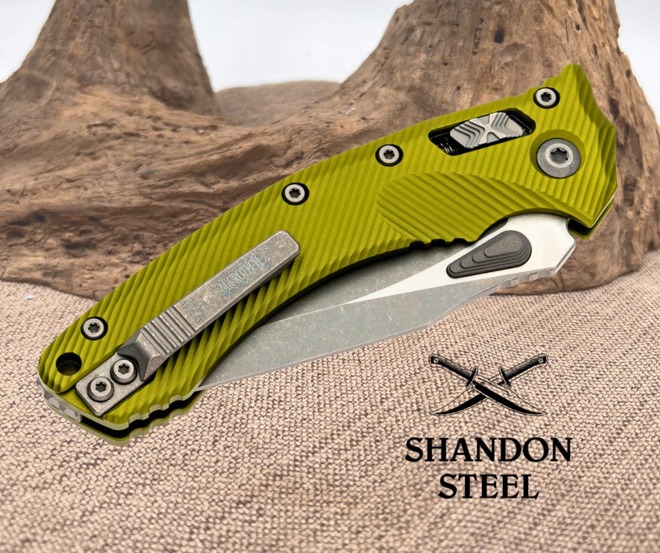 Green folding knife with metallic blade on a textured surface, Shandon Steel logo visible