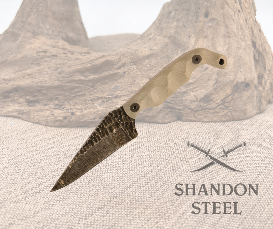 A knife with a grey handle and a patterned dark blade, resting against a textured backdrop with the text 'SHANDON STEEL' displayed.