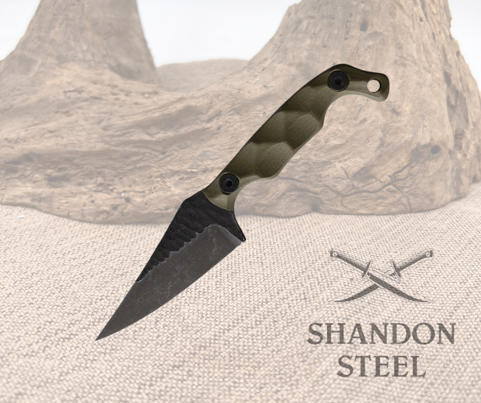A fixed blade knife with an OD green G10 handle and a black stonewash finish steel blade, placed on a textured surface with the text 'SHANDON STEEL' visible.