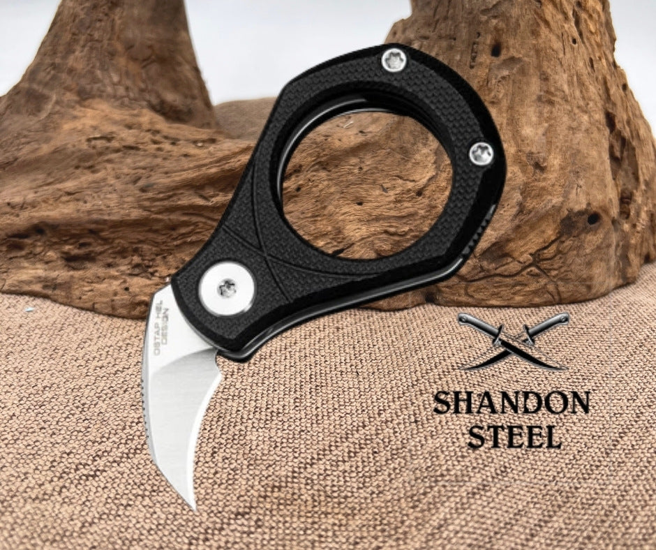Folding knife with black handle and silver blade on a textured surface with 'Shandon Steel' branding.
