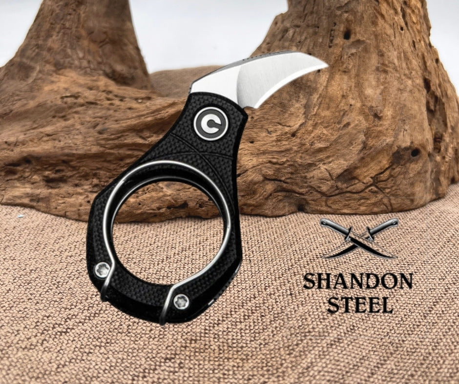 Folding knife with black handle and silver blade on a textured surface with 'Shandon Steel' branding.