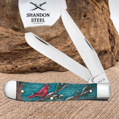 A double-blade pocket knife with a turquoise and red cardinal engraved handle, displayed against a rustic wood and burlap background. The brand logo 'Shandon Steel' is visible in the upper left.