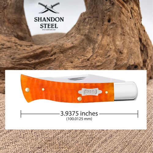 Shandon Steel folding pocket knife with a bright orange flamed handle and silver blade, shown on a white measurement card with dimensions and a rustic wood background.
