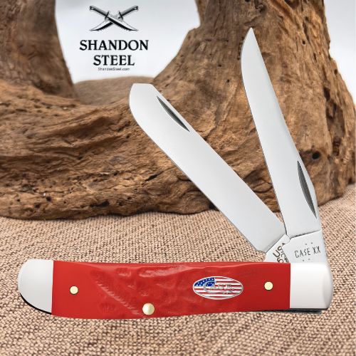 A red and white double-blade pocket knife with a small American flag emblem on the handle, displayed in front of a rustic wood prop. The brand name 'Shandon Steel' is visible in the upper left corner.
