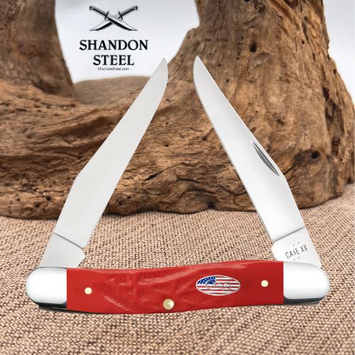 A two-blade folding pocket knife with a glossy red handle and brass pins, displayed against a rustic wood background with a burlap surface. The brand logo 'SHANDON STEEL' is visible in the upper left, and 'CASE XII' is engraved on the steel blade.