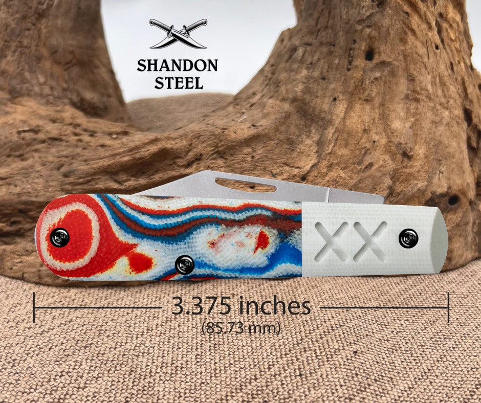 Folding knife with a colorful handle and Shandon Steel logo on a textured surface.