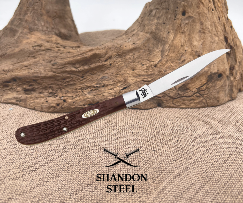 A Case XX Slimline Trapper knife with a brown delrin handle and stainless steel bolster, displayed against a natural background.