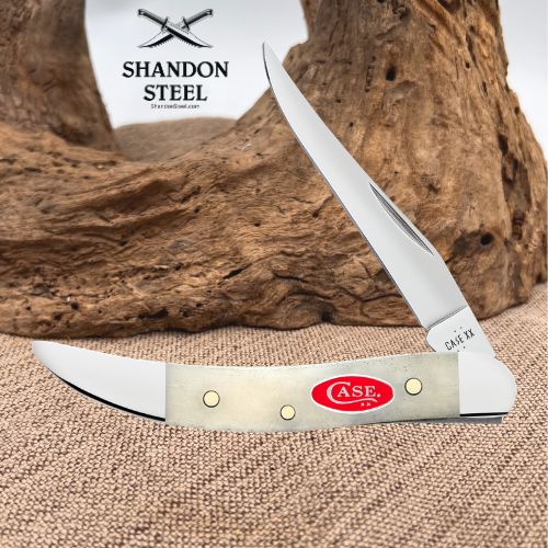 A folding pocket knife with a silver blade and a light beige handle, displayed on a burlap surface with a piece of driftwood in the background. The handle features a red oval CASE logo and the brand name 'SHANDON STEEL' is visible in the background.