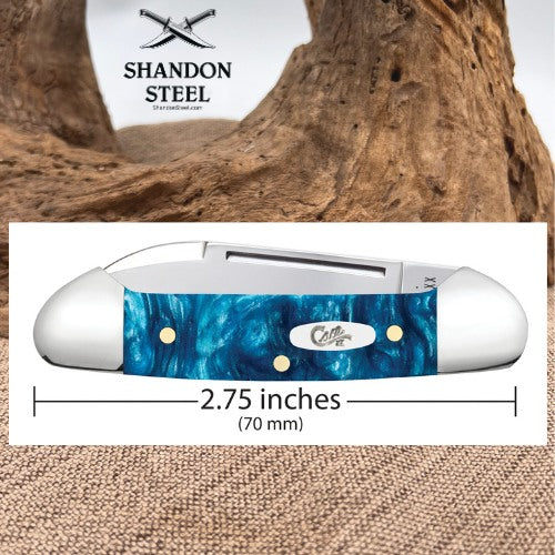 A pocket knife with a blue marbled resin handle and silver-toned metal hardware, shown on a white background with a wood-driftwood backdrop and a measurement label indicating 2.75 inches (70 mm).