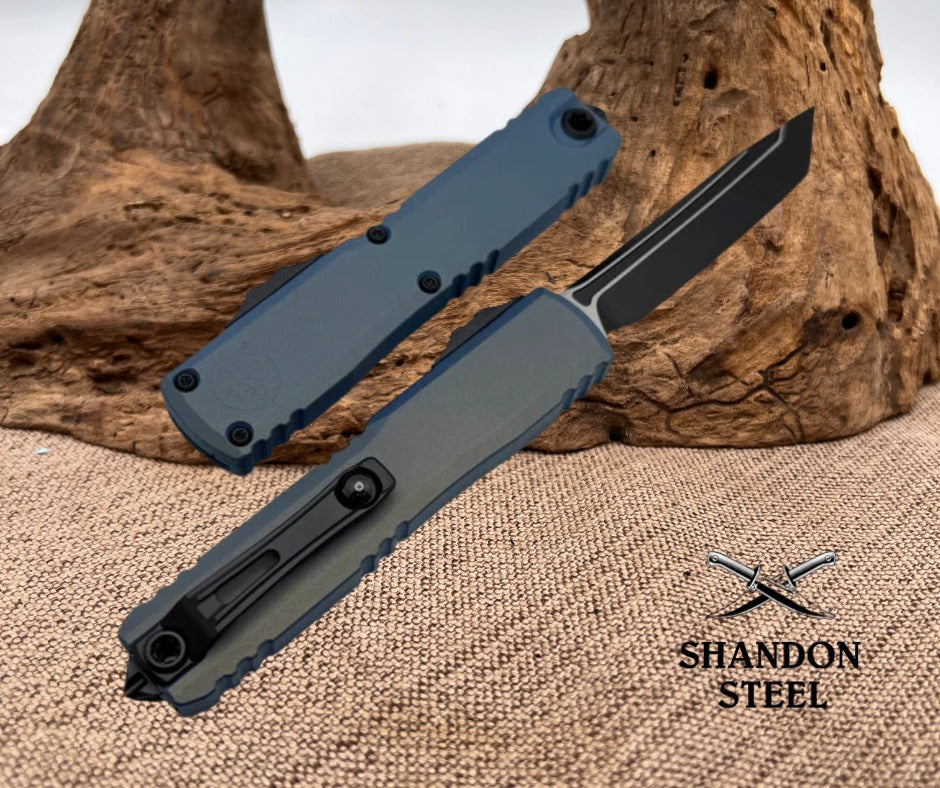 Folding knife with a gray handle and black blade on a textured surface with 'Shandon Steel' branding.