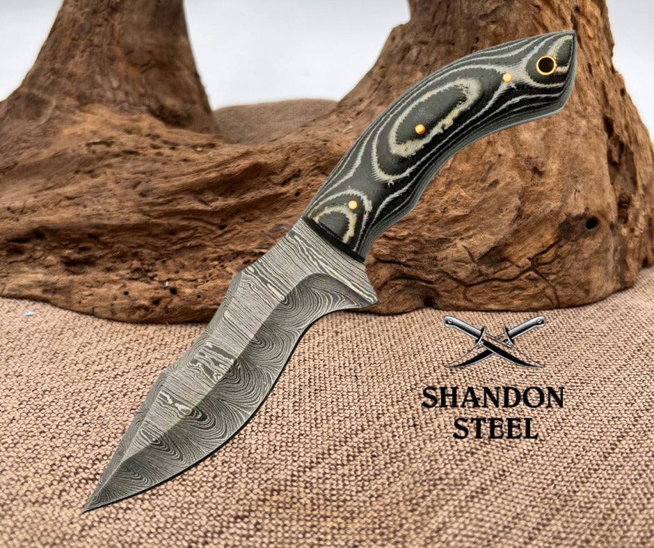 Decorative knife with a detailed handle on a textured surface, featuring the Shandon Steel logo.