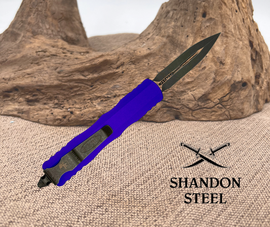 A purple OTF (Out the Front) knife with a double action mechanism and a glass breaker, displayed on a textured background with the brand 'Shandon Steel' visible.