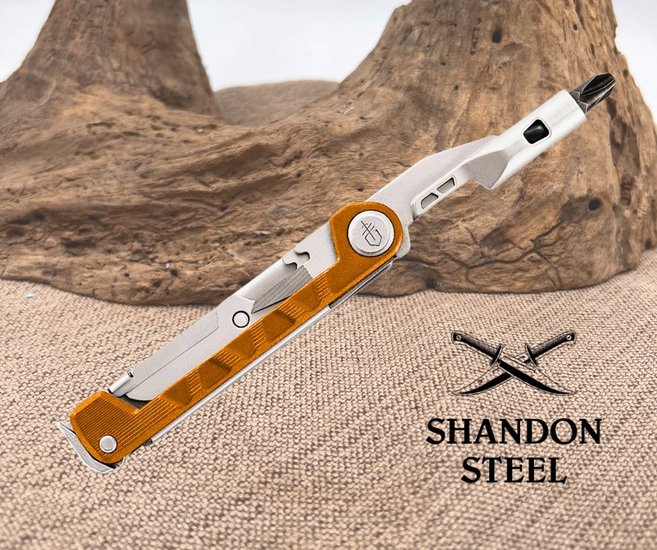 Folding knife with orange and silver design on a textured surface, featuring 'Shandon Steel' branding.