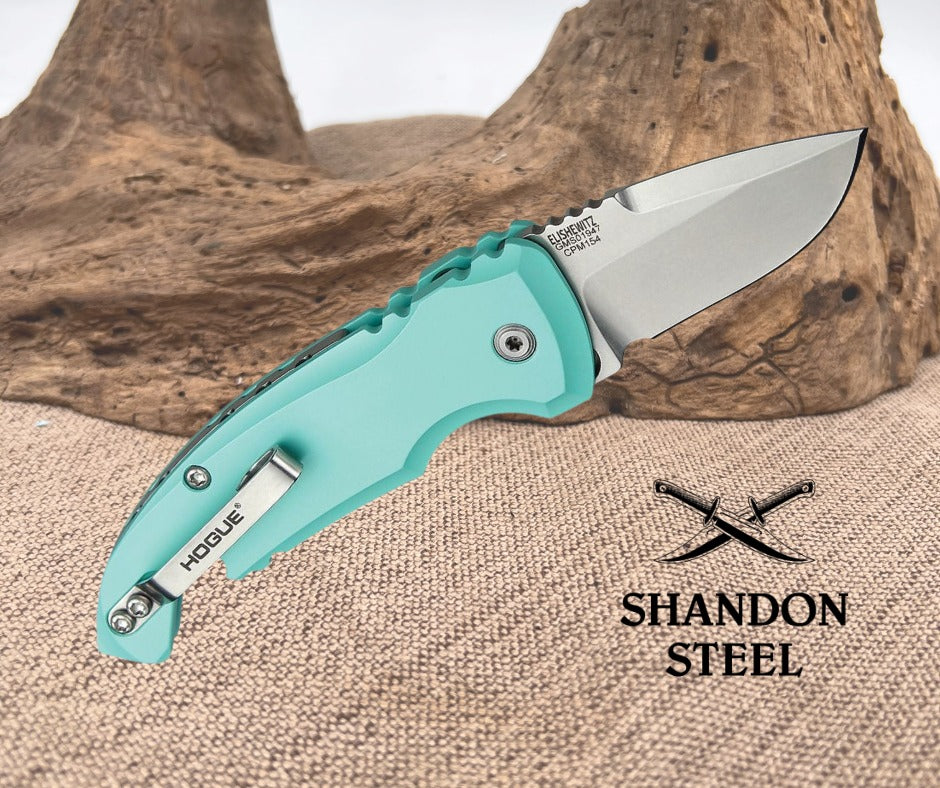 Teal folding knife with metallic blade on a textured surface, featuring 'Shandon Steel' branding.