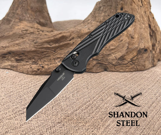 Black folding knife on a textured surface with 'Shandon Steel' branding.