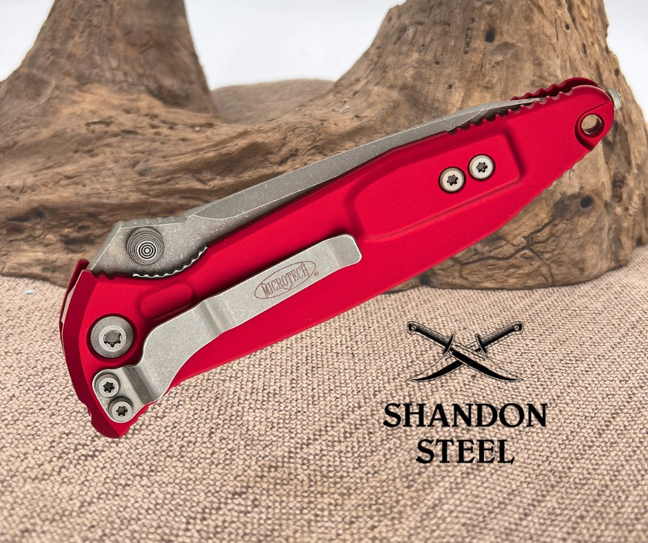 Red folding knife with silver blade on a textured surface, featuring Shandon Steel branding.
