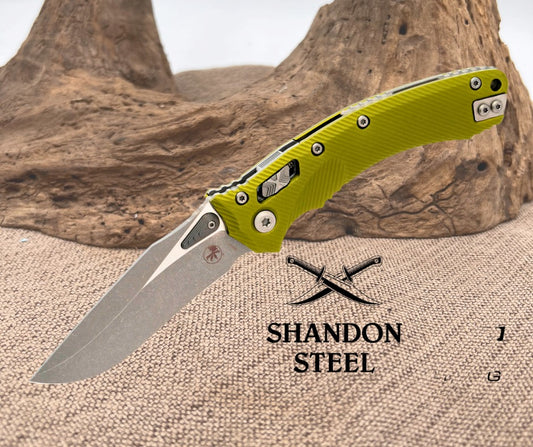 Folding knife with green handle on a textured surface, Shandon Steel logo visible