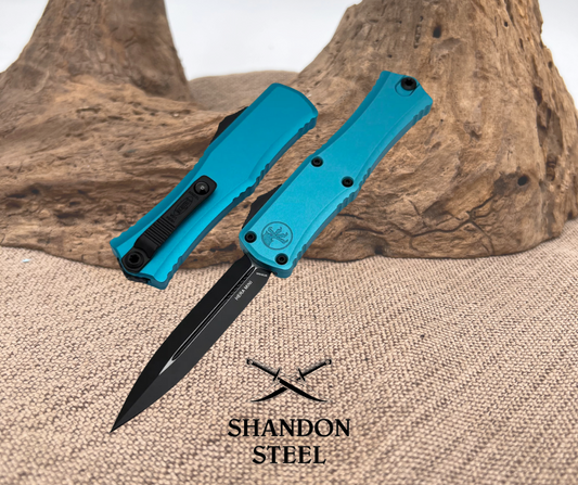 A Microtech HERA II MINI D/E knife with a black blade and turquoise aluminum handle, displayed open on a wooden surface.