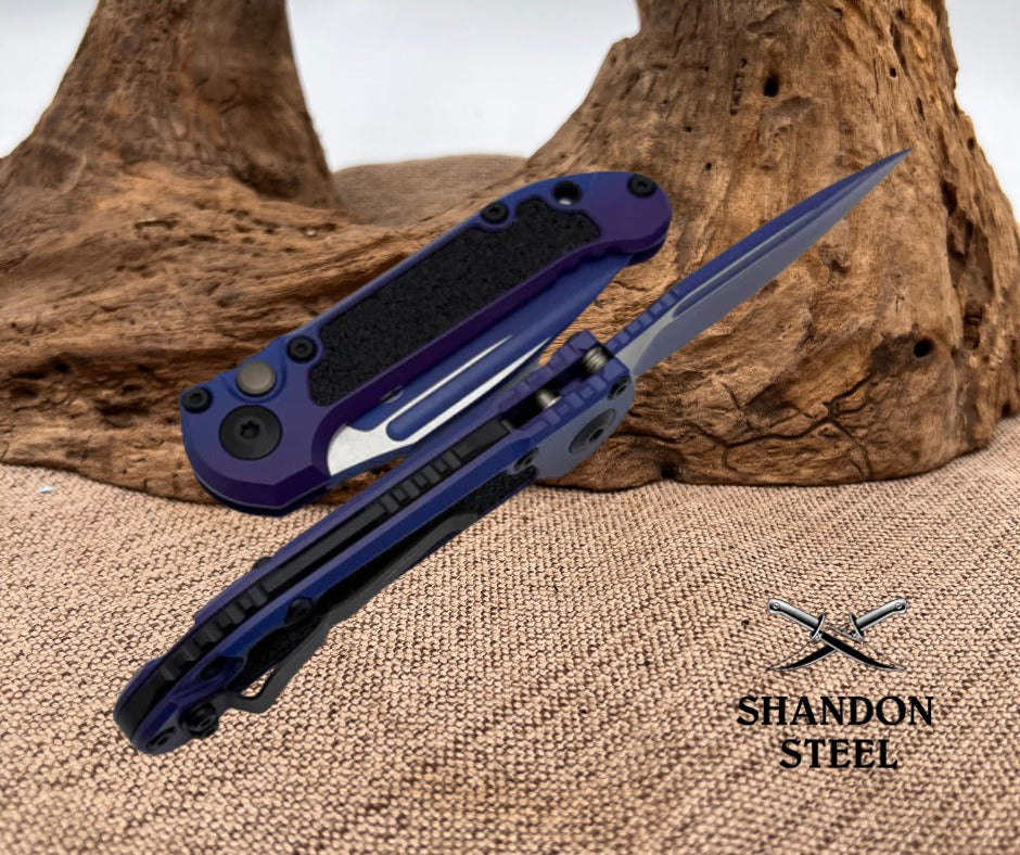 Blue and black folding knife on a textured surface with 'Shandon Steel' branding.