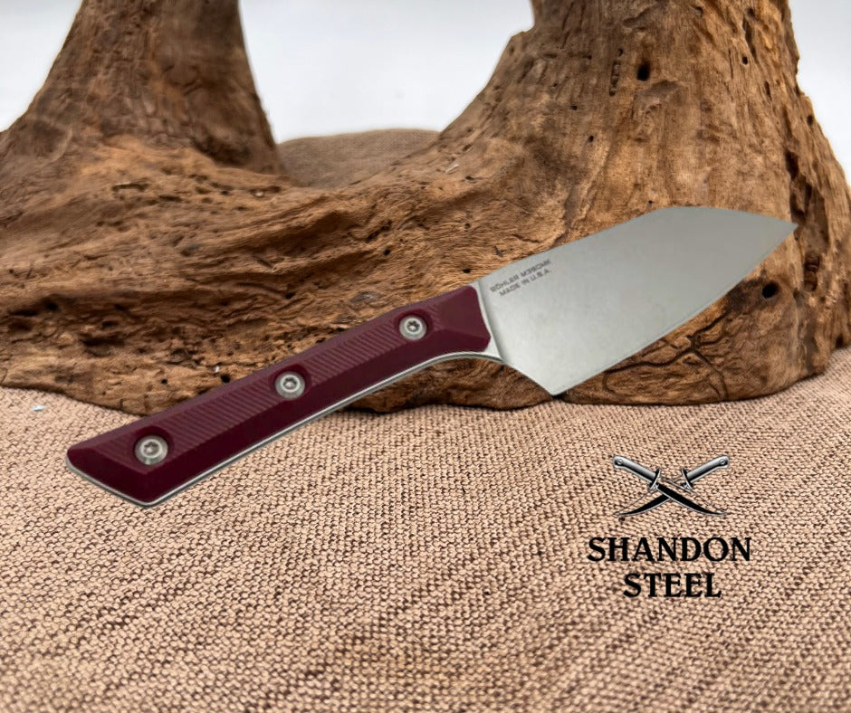 Knife with a red handle on a textured surface, Shandon Steel logo visible