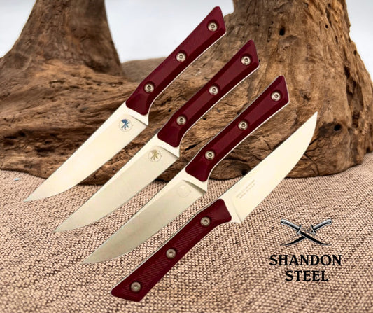 Four knives with red handles on a textured surface, branded 'Shandon Steel'.
