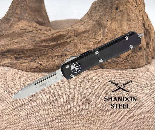 Folding knife with black handle and silver blade on a textured surface with 'Shandon Steel' branding.