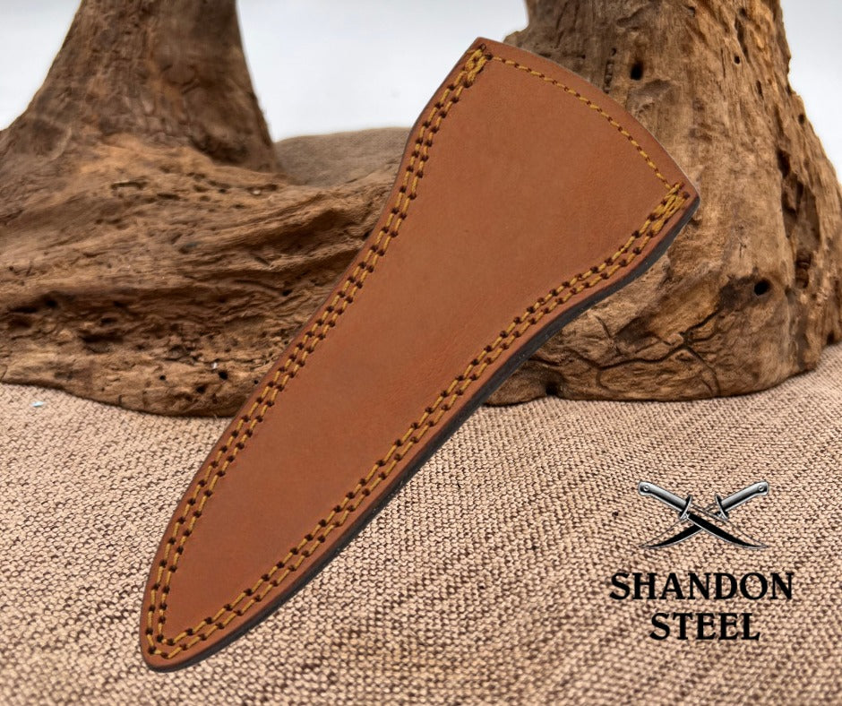 Brown leather knife sheath on a textured surface with 'Shandon Steel' branding.