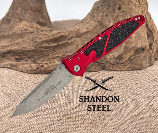 Red folding knife with black textured handle on a textured surface, Shandon Steel logo visible