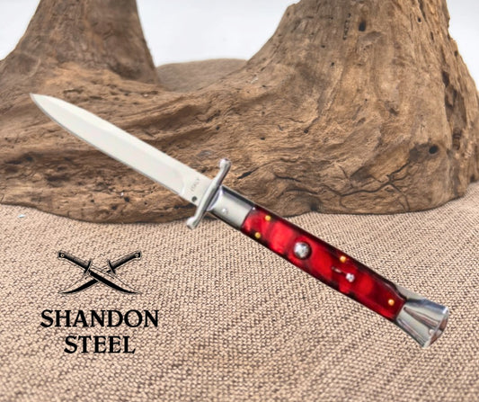  Dagger with red handle on a textured surface, branded 'Shandon Steel'.
