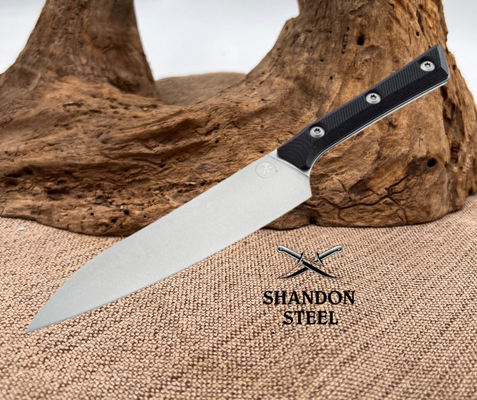 Knife with black handle and silver blade on a textured surface with 'Shandon Steel' branding.